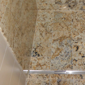 Dusche mit grossformatigen Natursteinplatten "Golden Crema" poliert, Boden mit Platten 300x600 geledert